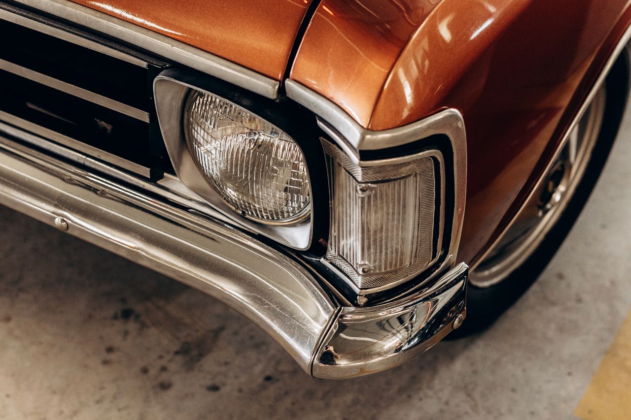 Detailed close-up of a vintage car's headlight and chrome bumper for classic car enthusiasts.