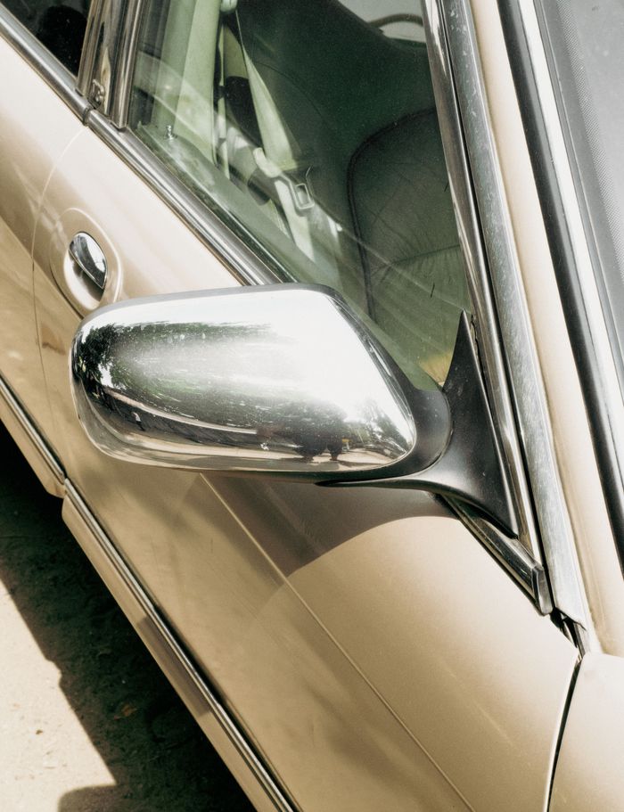 Home Shiny chrome side mirror of an antique beige car reflecting sunlight outdoors.