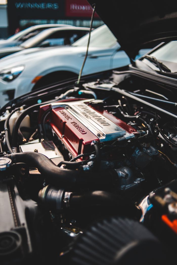 Black small oil filter and modern red battery surrounded by wires of inner part of contemporary automobile